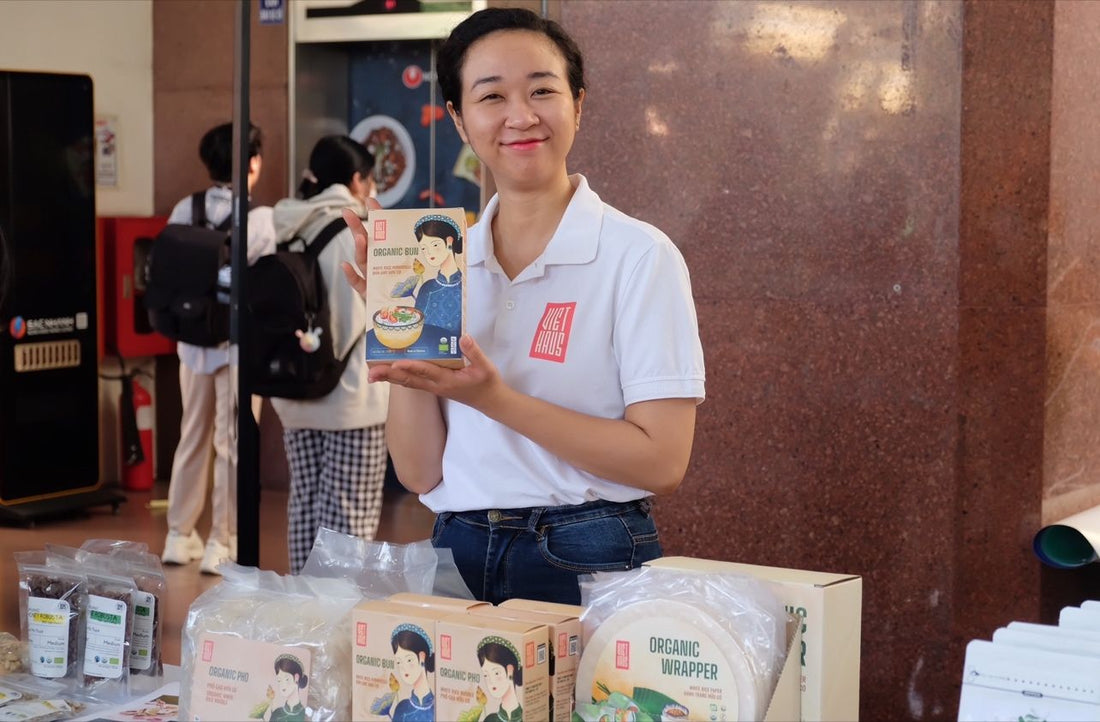 Woman holding a box of organic pho noodles next to other organic Vietnamese food products.