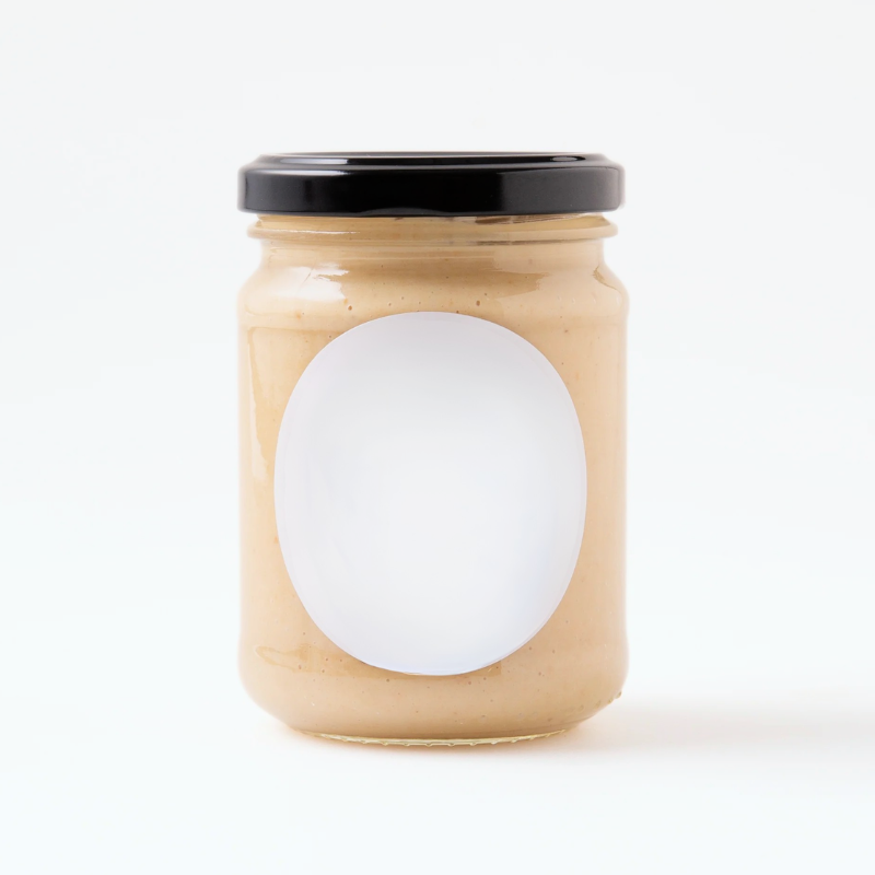 Jar of peanut butter with a white label on a white background