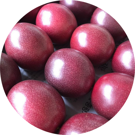 Close-up of a pinkish-red organic passion fruit showing its natural spherical shape and smooth skin texture