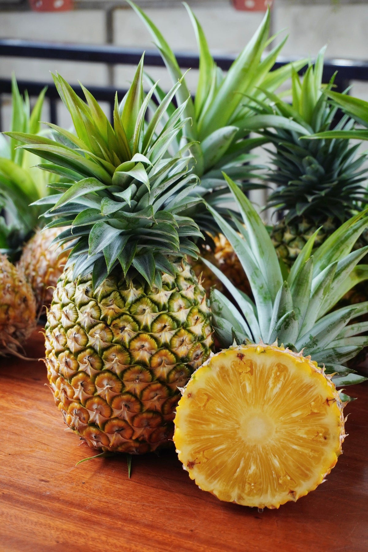 Fresh organic pineapple on a wooden surface, with one sliced open to show the ripe yellow interior.
